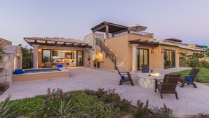 A two-story house with a stone exterior, a patio with outdoor seating, and a fire pit.