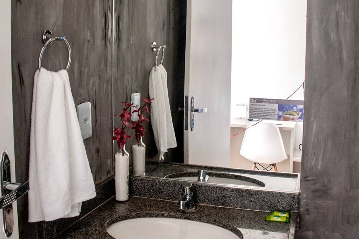 A modern bathroom with a dark wood wall, a granite countertop, a white sink, and a mirror.