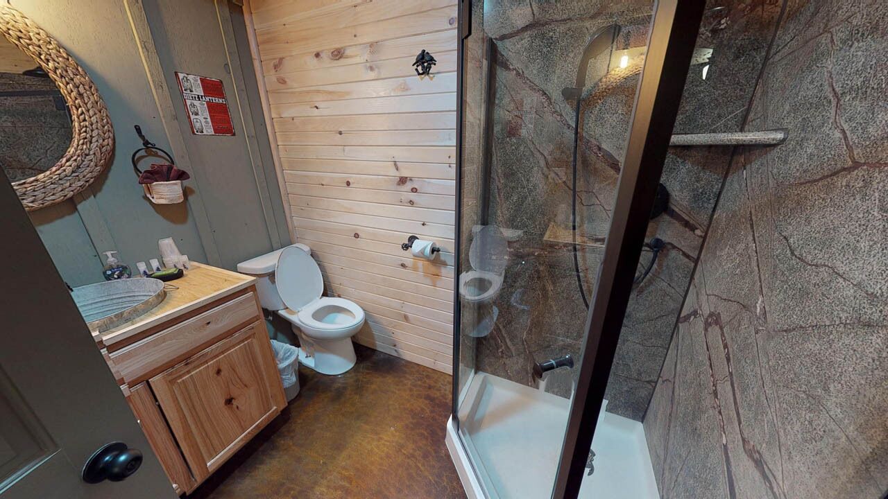 A bathroom with a wooden vanity, a toilet, and a glass-enclosed shower area.