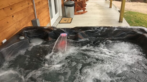 Ein Whirlpool mit sichtbarer Wasserleitung und einem Holzdeck im Hintergrund.