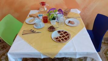 A dining table set with plates, cutlery, a pitcher, a cup, and a bowl of nuts.