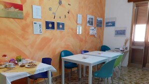 A dining area with tables and chairs, a clock on the wall, and various framed pictures. - Giosy (Portopalo di Capo Passero)