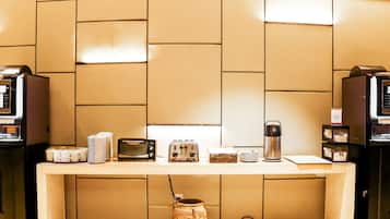 A kitchenette with a coffee machine, toaster, and a kettle on the counter.