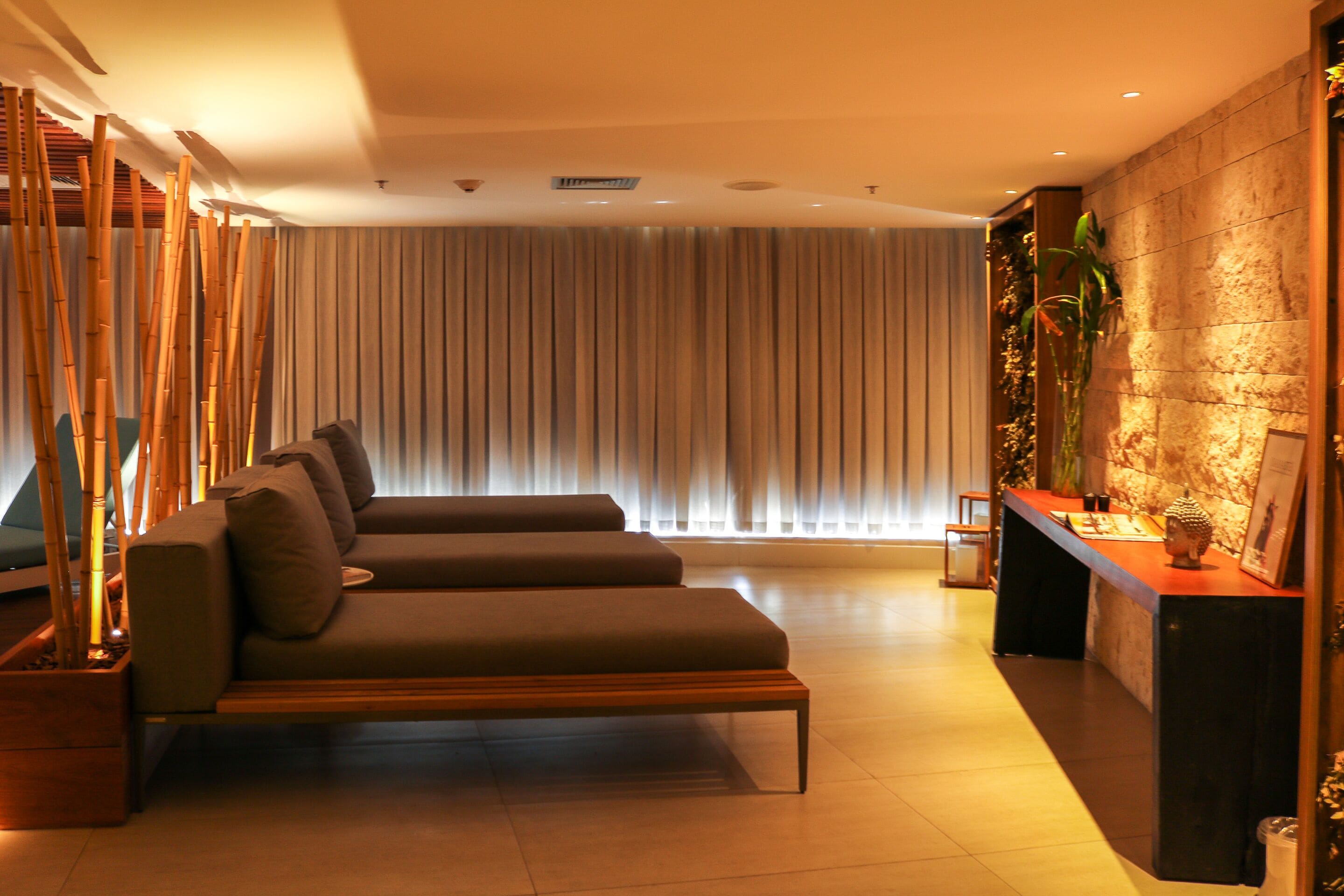 A modern living area with a sofa set, a reception desk, and a large window with curtains.