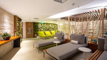 A modern lounge area with two sofas, a small table, and a wooden bench.