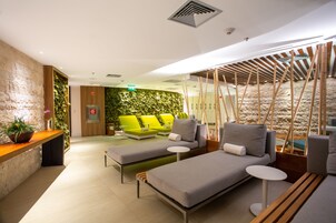 Un espace de détente moderne comprenant deux canapés, une petite table et un banc en bois.