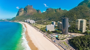 Un paisaje urbano costero con una playa, edificios altos y una montaña destacada al fondo.