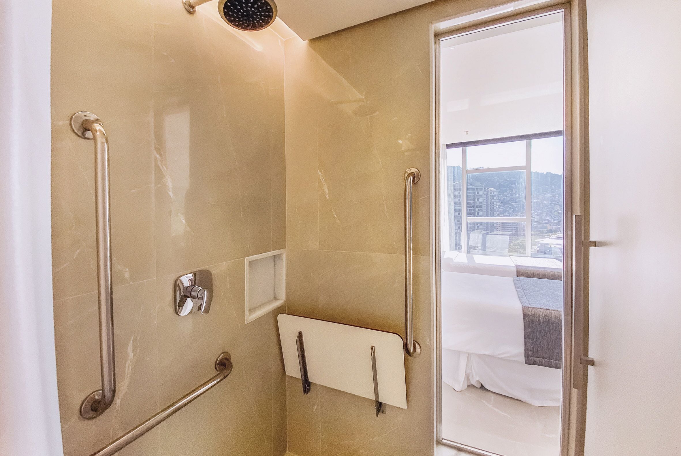 A bathroom with a glass shower door, a handrail, and a towel rack.