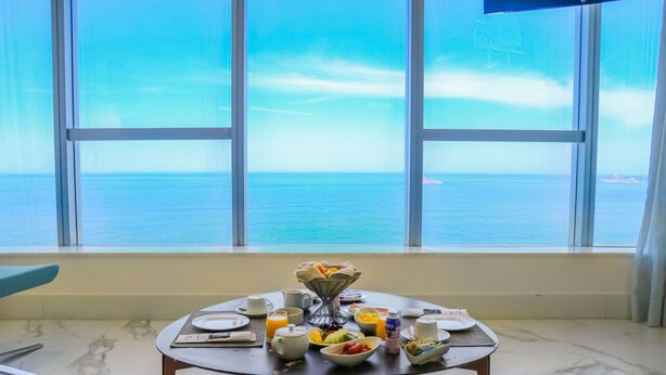 A breakfast table with various dishes and a view of the sea through large windows. - Hotel Nacional Rio de Janeiro OFICIAL (Rio de Janeiro)