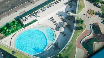 Relax by the pool surrounded by lush greenery and palm trees.