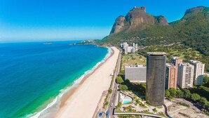 A coastal cityscape with a beach, high-rise buildings, and a prominent mountain. - Hotel Nacional Rio de Janeiro OFICIAL (Rio de Janeiro)