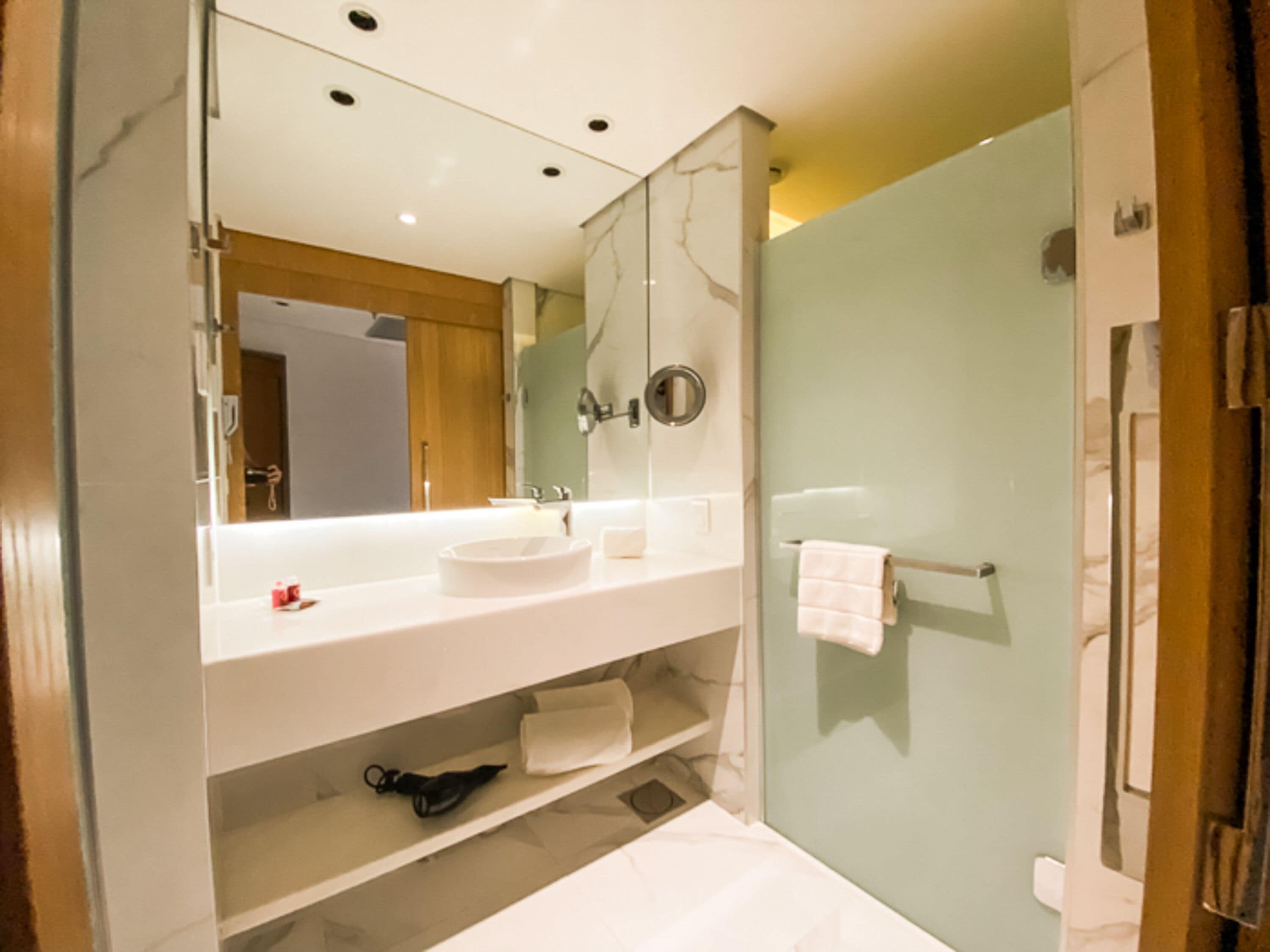 Un baño moderno con un espejo grande, tocador blanco y cabina de ducha de vidrio.