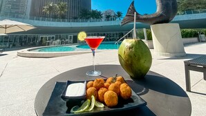 A dining area with a pool, a tall building, and a statue. - Hotel Nacional Rio de Janeiro OFICIAL (Rio de Janeiro)