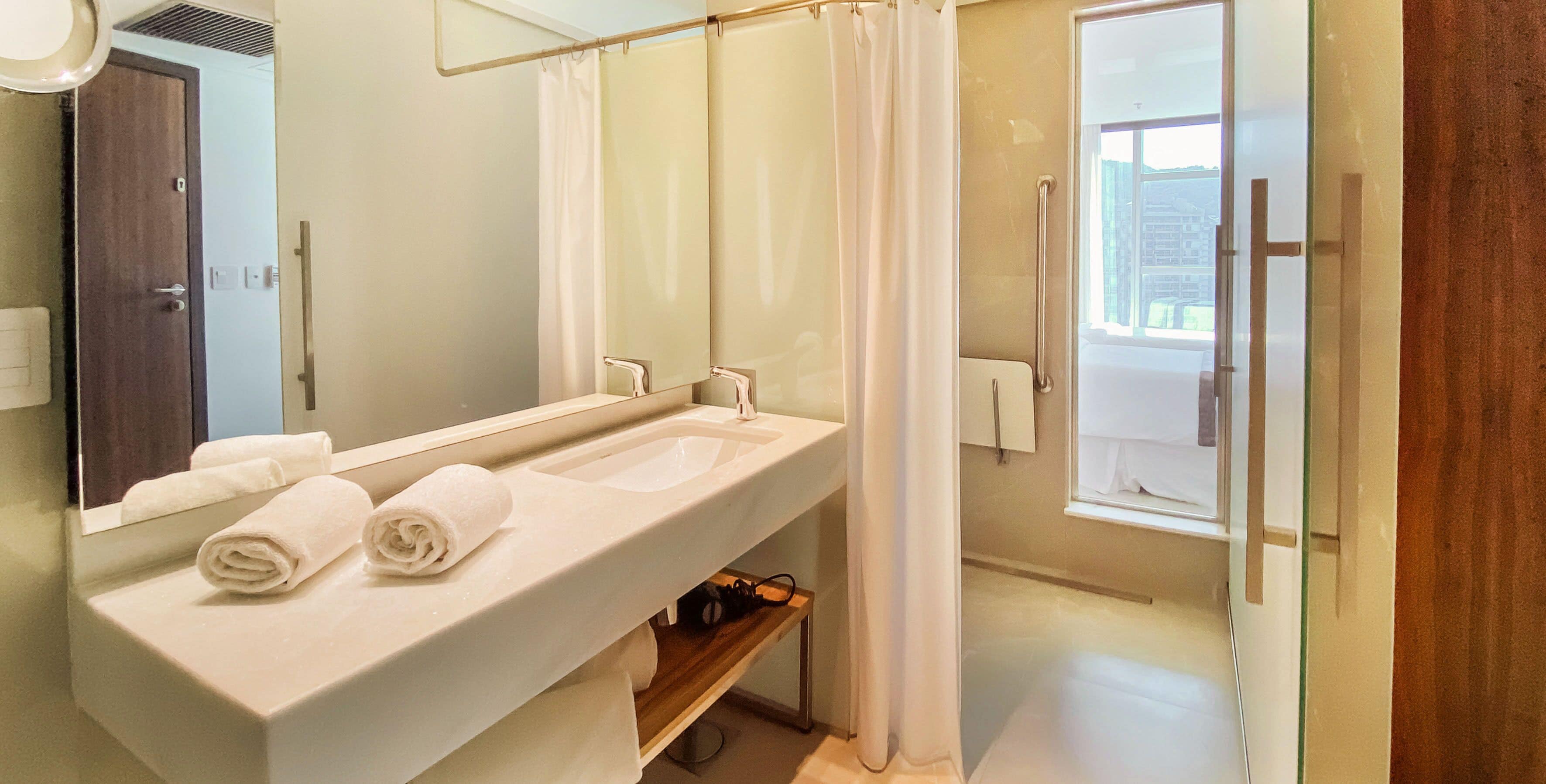 A modern bathroom with a dual sink vanity, a large mirror, and a shower area.