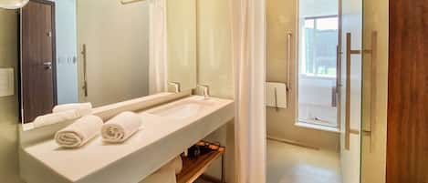 A modern bathroom with a dual sink vanity, a large mirror, and a shower area.