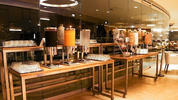 Uma área de buffet com diversos distribuidores de alimentos e uma vitrine de vidro.