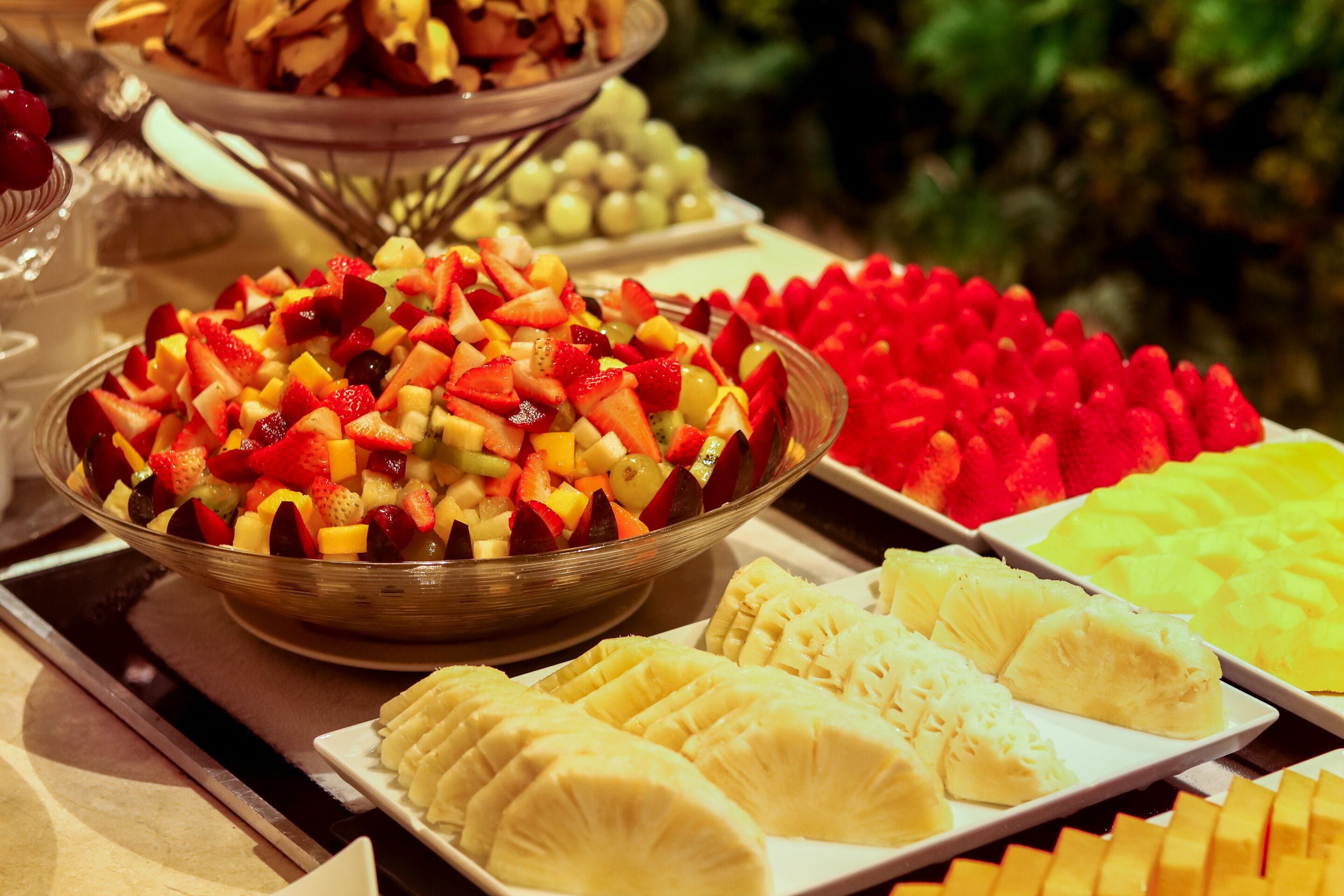 A buffet with various fruits and a bowl of mixed fruit salad.