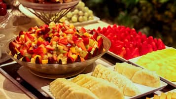 Un bufé con diversas frutas y un tazón de ensalada de frutas variadas.