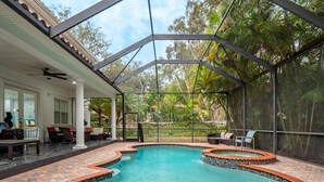 A covered outdoor swimming pool with a curved design, surrounded by a brick deck and a glass enclosure. - ⭐️S. Tampa Mansion🔥Heated Pool+Spa🎬Movie Theater Chef’s Kitchen 5000sqft (Tampa)