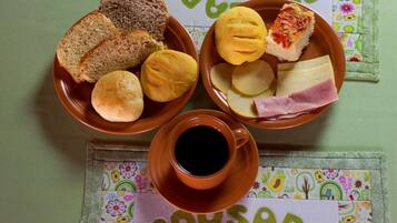 Ein Tisch mit Brot, Käse, Schinken und einer Tasse Kaffee.