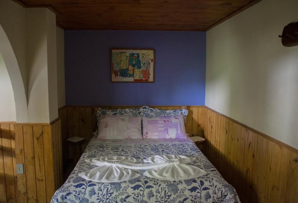 A bedroom with a wooden headboard, a floral-patterned bedspread, and a painting on the wall.