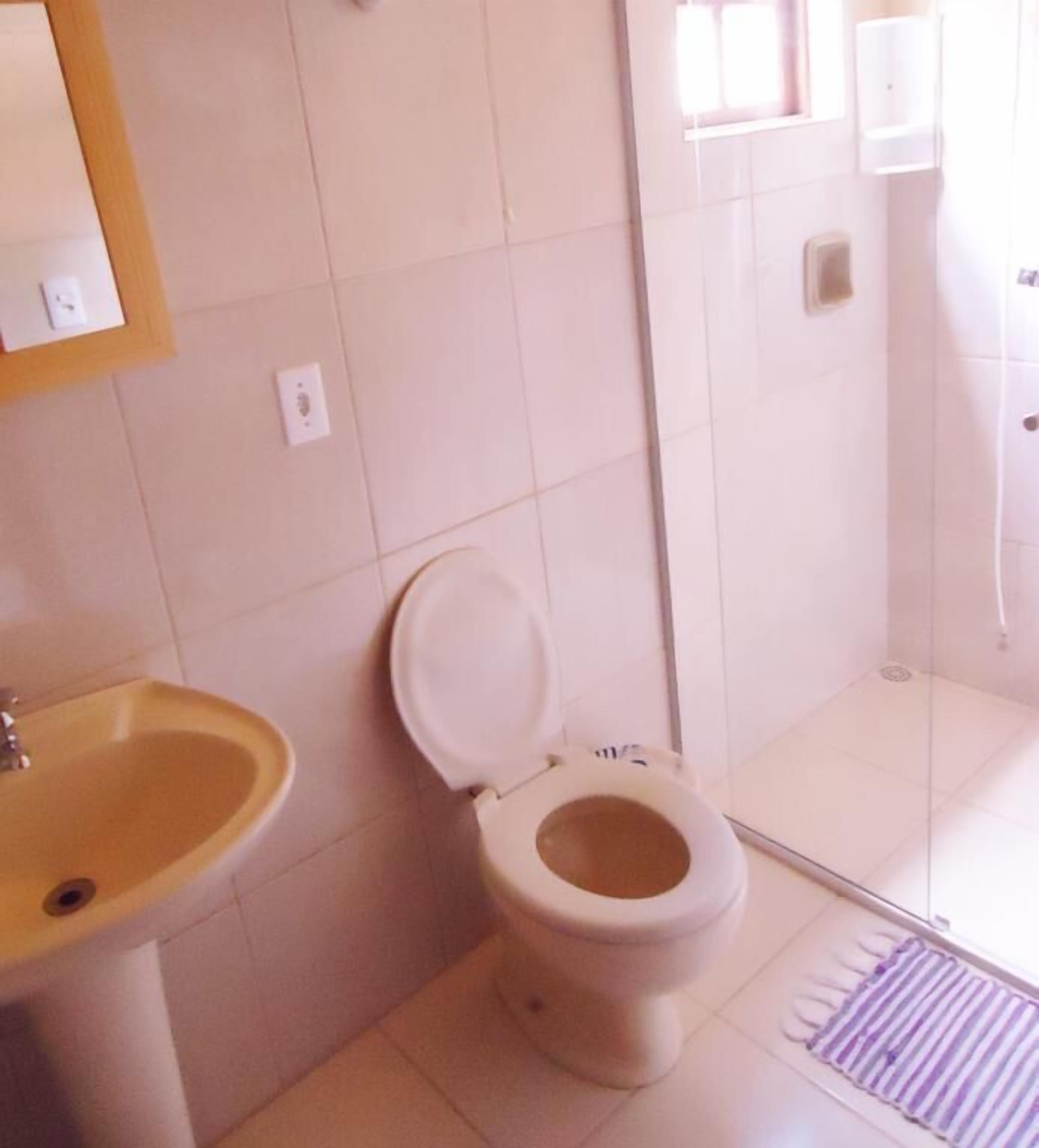 A bathroom with a toilet, sink, and shower area.