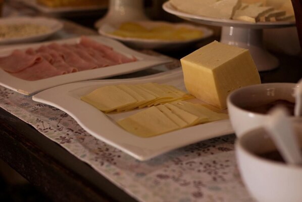 Een buffet met verschillende gerechten, zoals kaas, ham en een kom soep.