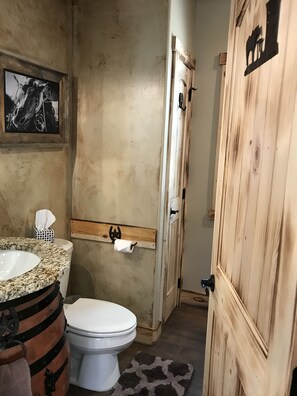 Een rustieke badkamer met een houten deur, een marmeren wastafel en een toilet.