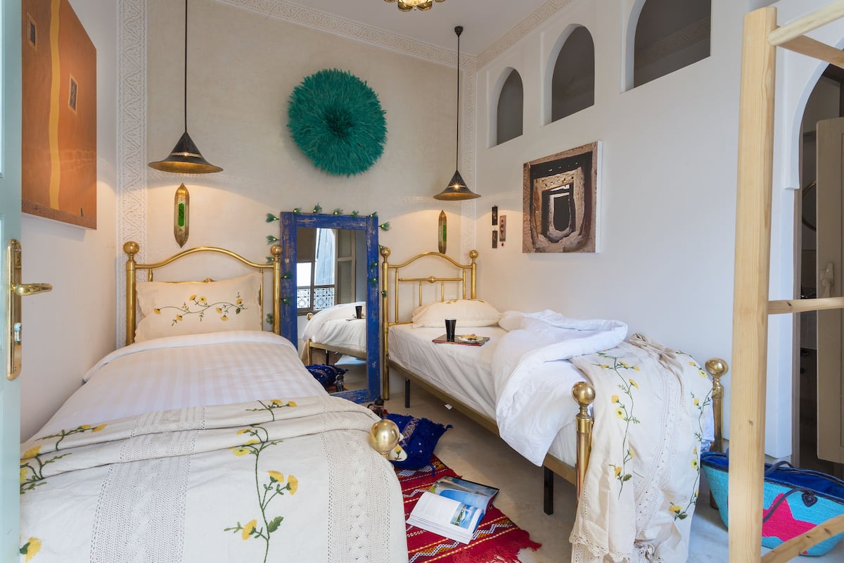 Quarto com duas camas, um espelho e um objeto decorativo na parede.