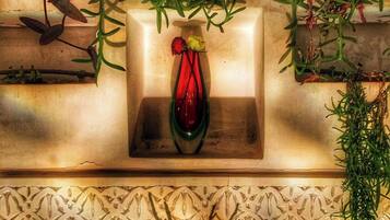 A decorative shelf with a vase containing flowers, surrounded by greenery.