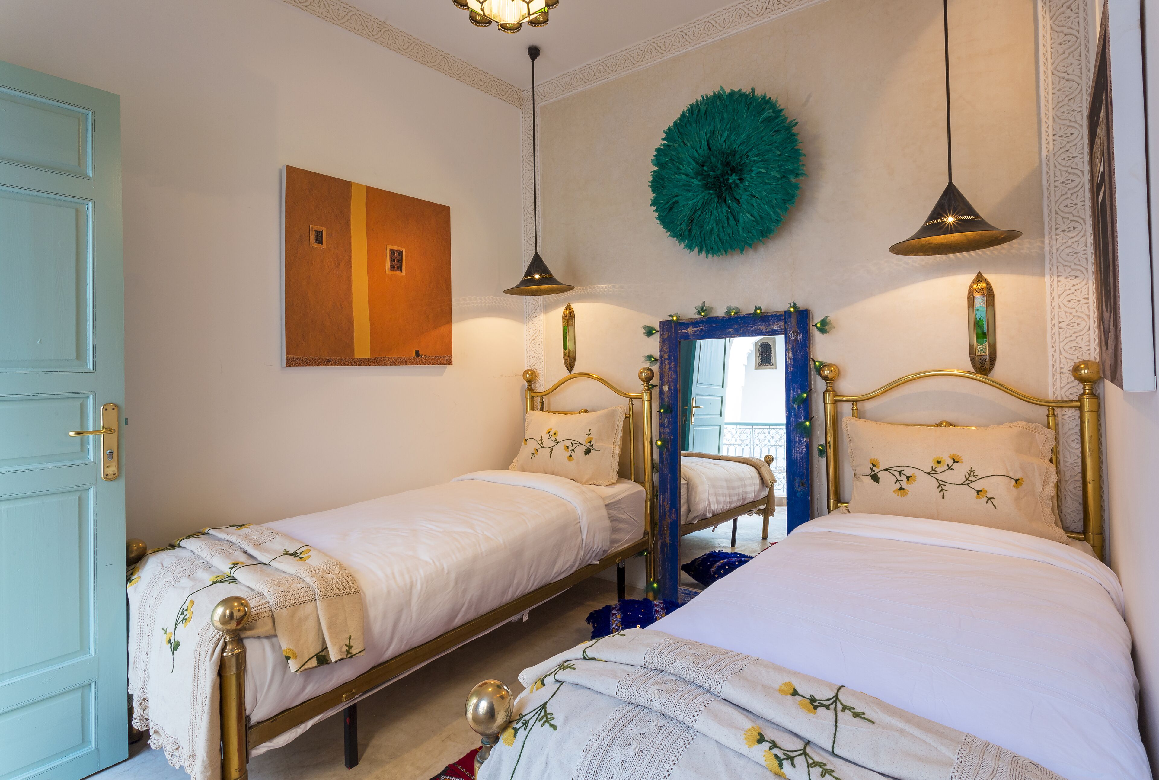 A bedroom with two single beds, a mirror, and decorative wall hangings.