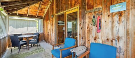 Una cabaña de madera con un porche cubierto, una mesa de comedor con sillas y un sofá azul.