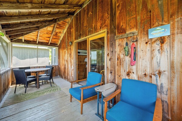 A wooden cabin with a covered porch, a dining table with chairs, and a blue sofa. - Hunter Cove Cabin #4 in the Hunter Cove Cabins Community! (Rangeley)