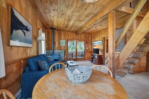 A wooden interior with a sofa, a table with a basket, a fireplace, and a staircase. - Hunter Cove Cabin #4 in the Hunter Cove Cabins Community! (Rangeley)