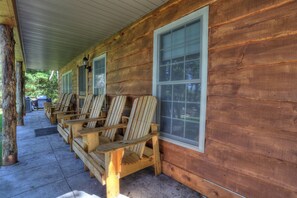 Une cabane en bois dotée d’un porche aménagé avec des fauteuils Adirondack.