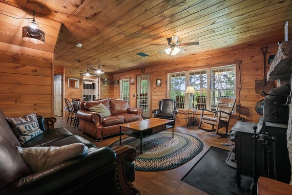A cozy cabin interior with a wooden ceiling, leather furniture, and a fireplace.