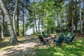 A campsite with a fire pit and Adirondack chairs.