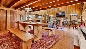 Un intérieur de chalet en bois spacieux, comprenant un coin repas, un piano et une cheminée en pierre.