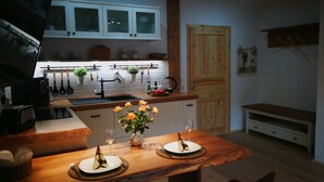 A modern kitchen with a wooden countertop, a built-in sink, and cabinets. There is a dining table set with plates and a vase of flowers.
