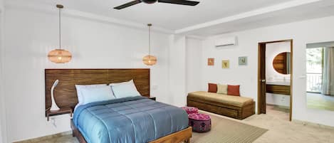 A bedroom with a wooden bed, a ceiling fan, hanging lamps, a bedside table, a bench, and a view of the outdoors.