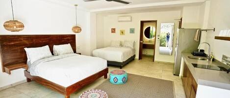 A bedroom with a wooden bed, two bedside tables, a ceiling fan, and a view into the bathroom.