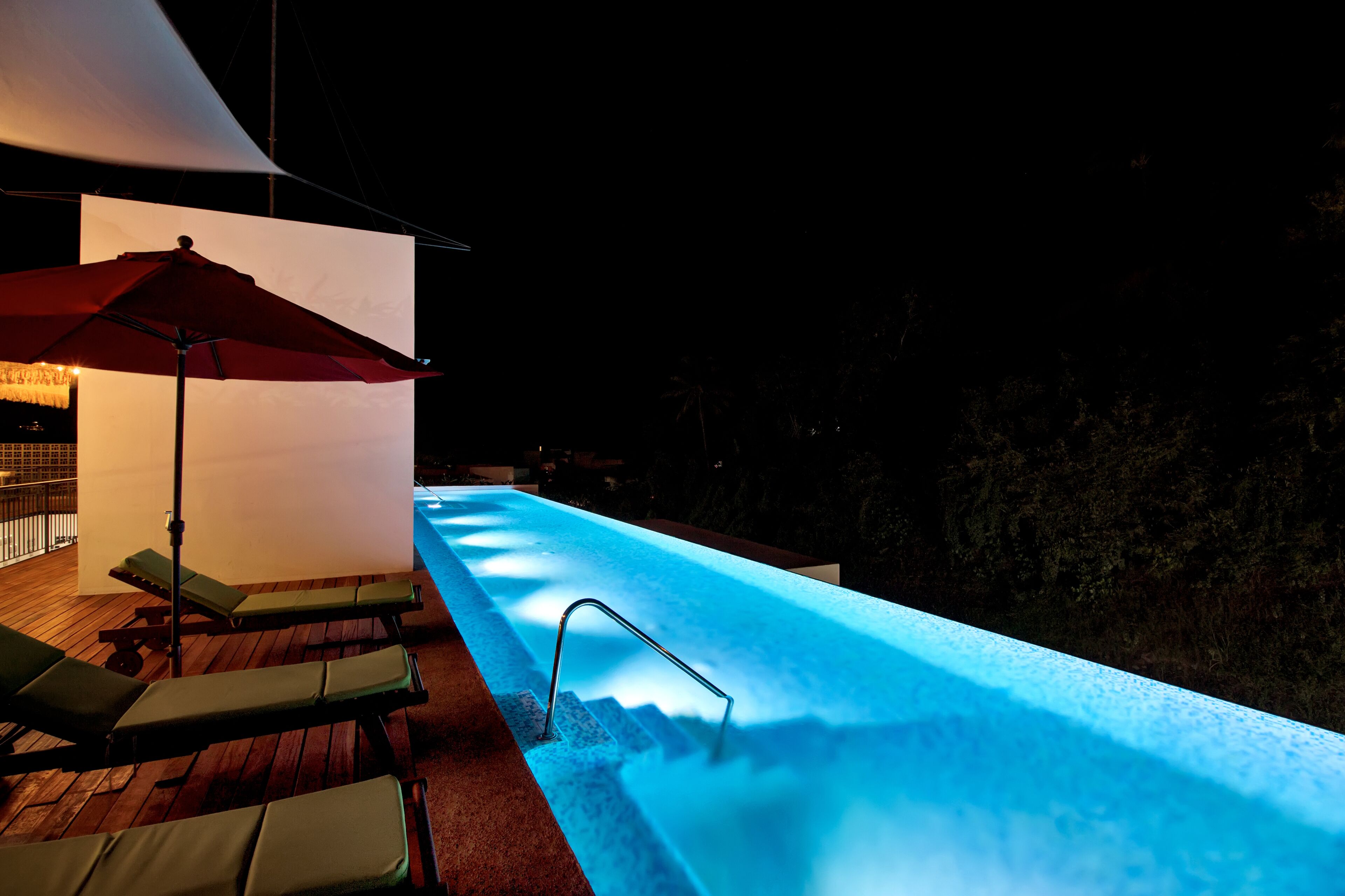 A heated outdoor pool with lounge chairs and an umbrella.