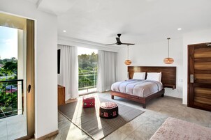 Un dormitorio moderno con una cama grande, un ventilador de techo y vistas a la vegetación.
