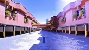 A row of pink buildings with balconies, each with a potted plant. - Motel Villa di Roma - Adults Only (Guarujá)
