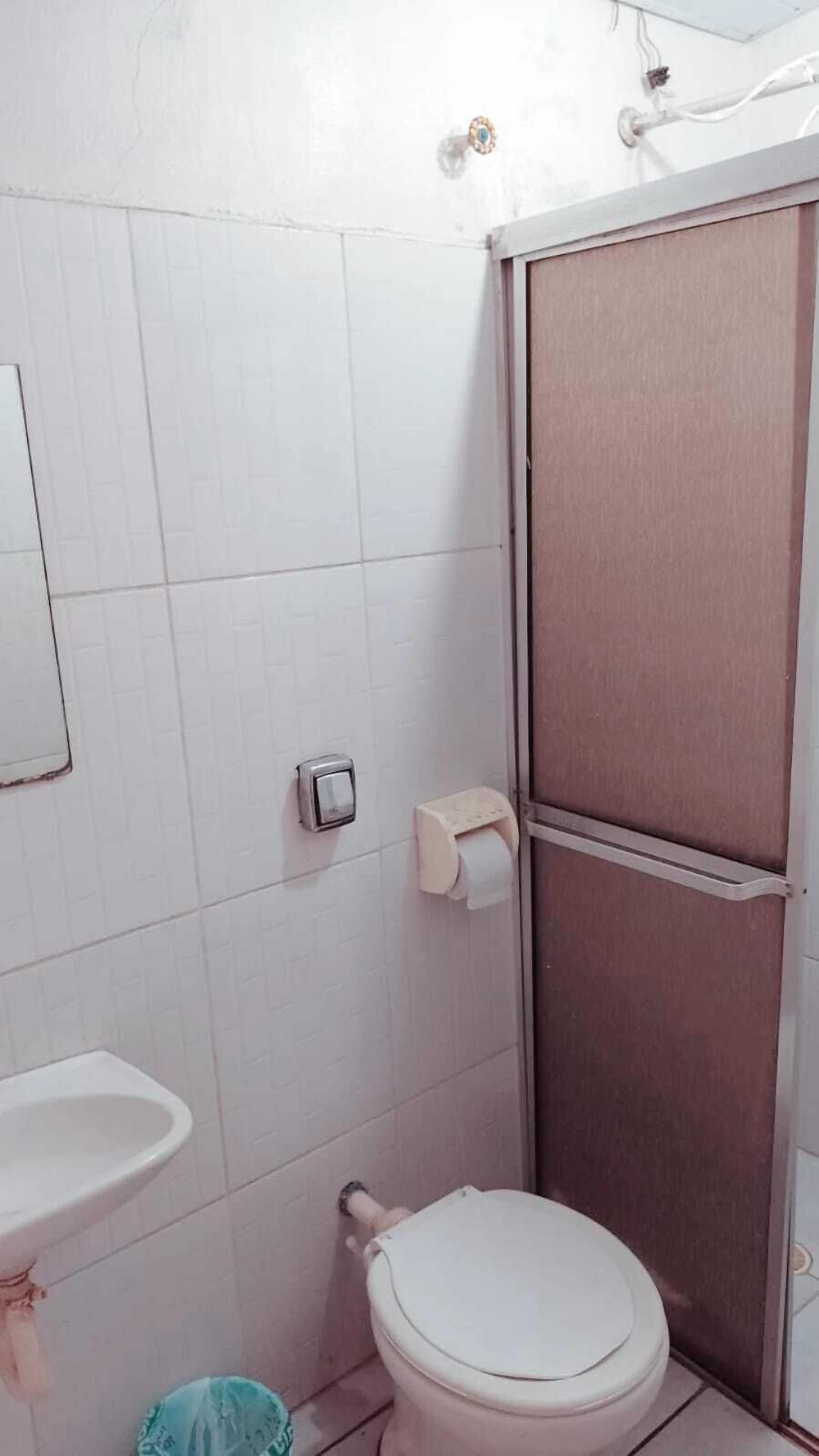 Uma casa de banho pequena com sanita, lavatório e cabine de duche.