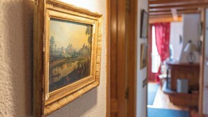 A framed painting on a wall, a wooden door, and a glimpse of a room with a counter and red curtains. - Apartment Angelique - Alpine duplex in Montgenevre (Montgenèvre)