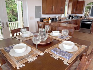 A dining area with a wooden table set for four, including bowls, wine glasses, and cutlery.