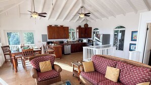 A spacious living area with wicker furniture, a dining table, and a kitchen in the background. - Experience the ultimate retreat at One Particular Harbour, where breathtaking views meet unparalleled privacy, creating the perfect oasis for relaxation and rejuvenation. This is the getaway you’ve been dreaming of! (Coral Bay)