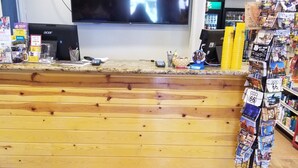 A reception area with a wooden counter, a computer, and a magazine rack.