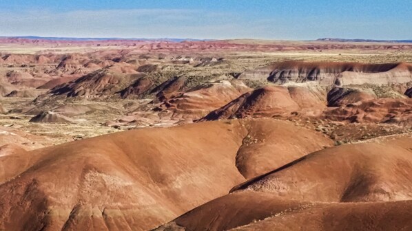 A panoramic view of a rugged landscape with undulating hills and a clear sky.